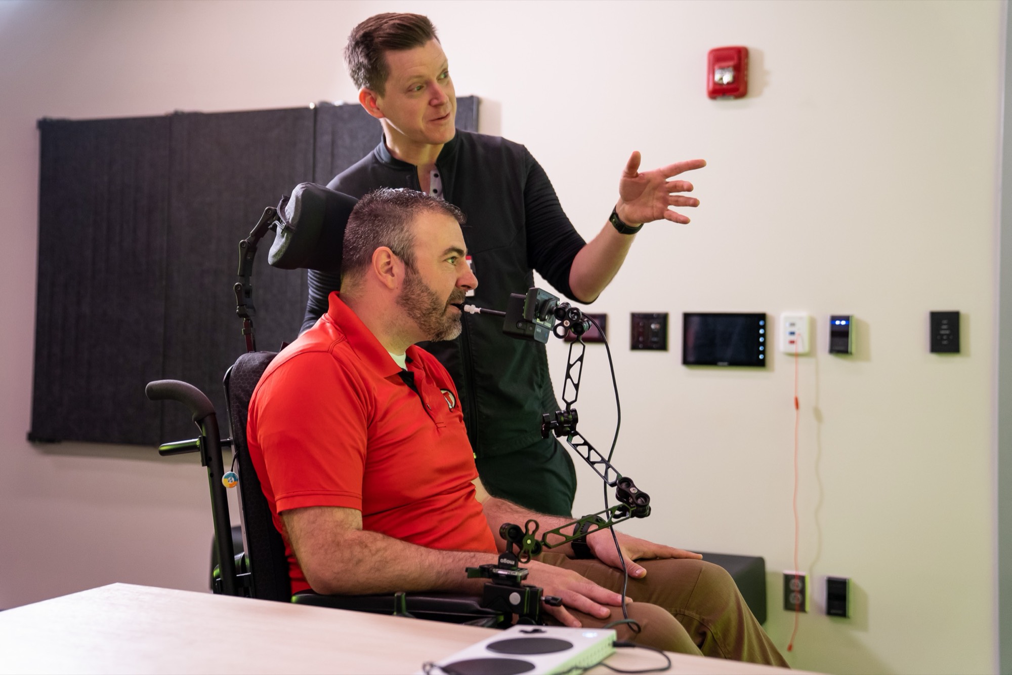 A clinician showing a patient the sip-and-puff controls in a hospital room